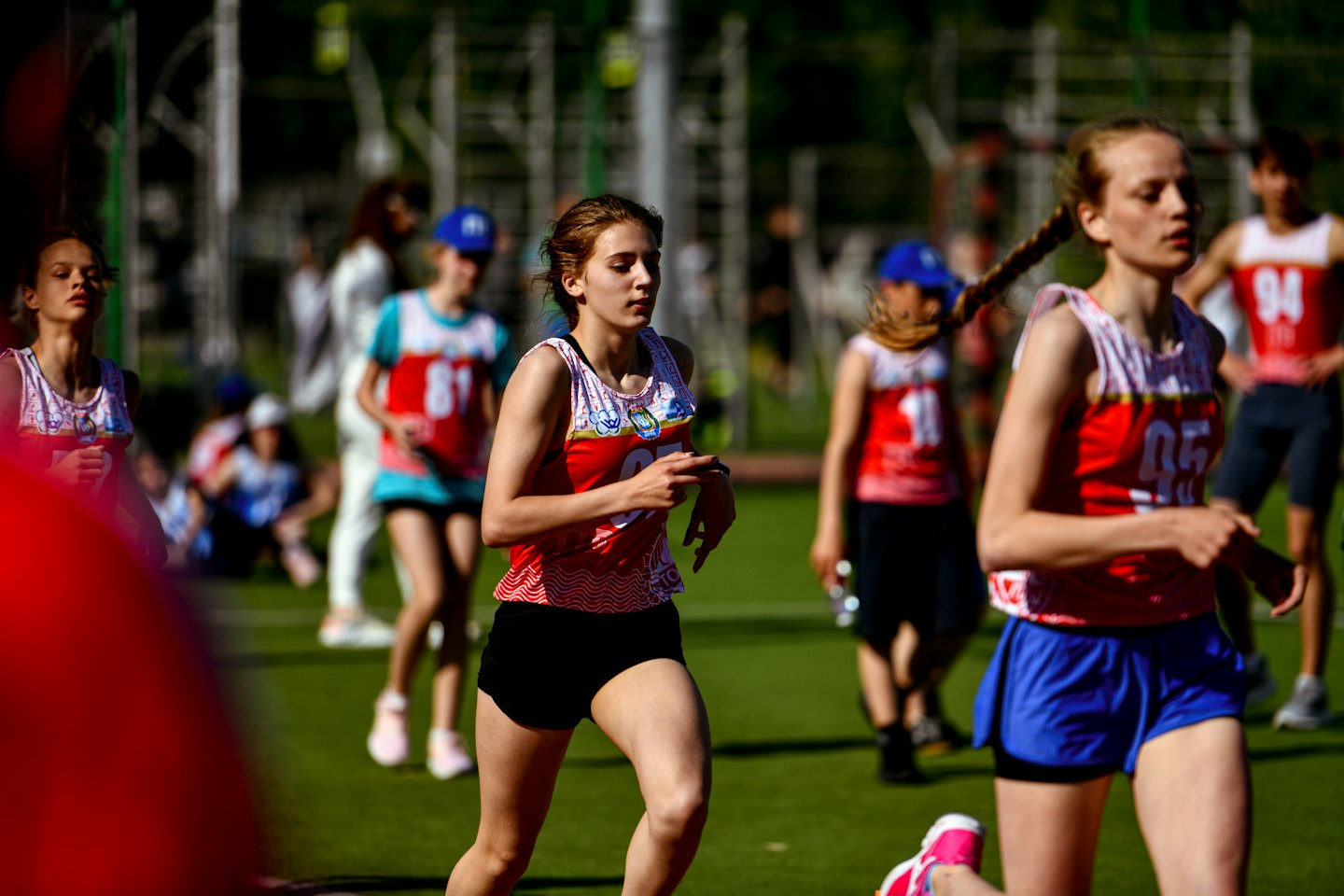 Atleti in maglia rossa e bianca che corrono su una pista.